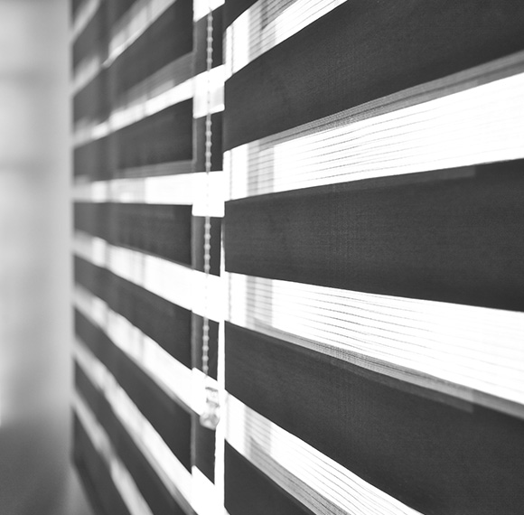 Faux wood blinds partially opened, allowing light to filter through.