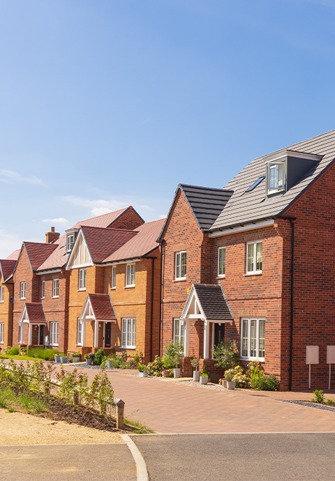 Newly built homes with landscaped front gardens and blue skies.