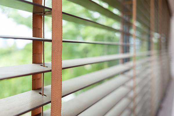 Fauxwood blinds with a view of green foliage in the background