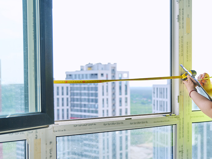 Measuring window dimensions for made-to-measure commercial blinds installation.