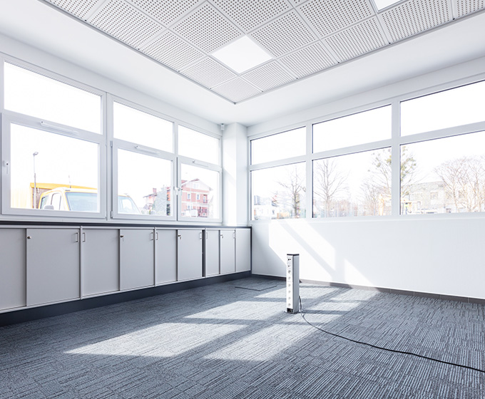 Brightly lit office space with large windows and grey cabinets, suitable for commercial blinds.
