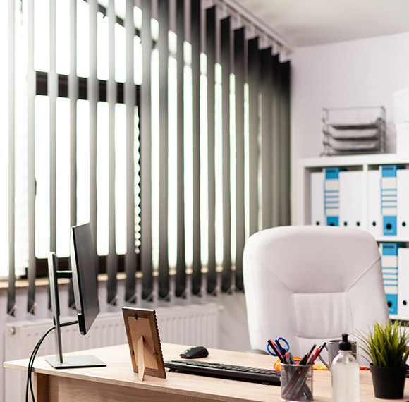 Modern office interior featuring fabric vertical blinds and a desk.