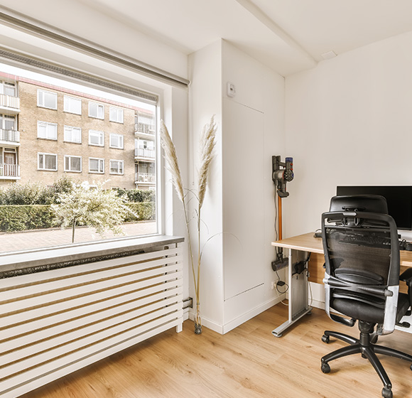 Horizontal striped roller blind fitted to large office window with wooden flooring and workspace visible