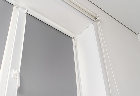 Gray roller blinds installed in a window with white trim.