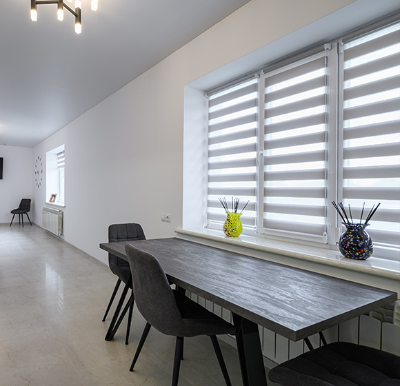 Modern interior with roller blinds, wooden table, and stylish vases.